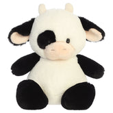 A cow plush toy from Aurora with tiny limbs, a black-and-white pattern, and a plump bean-weighted body.