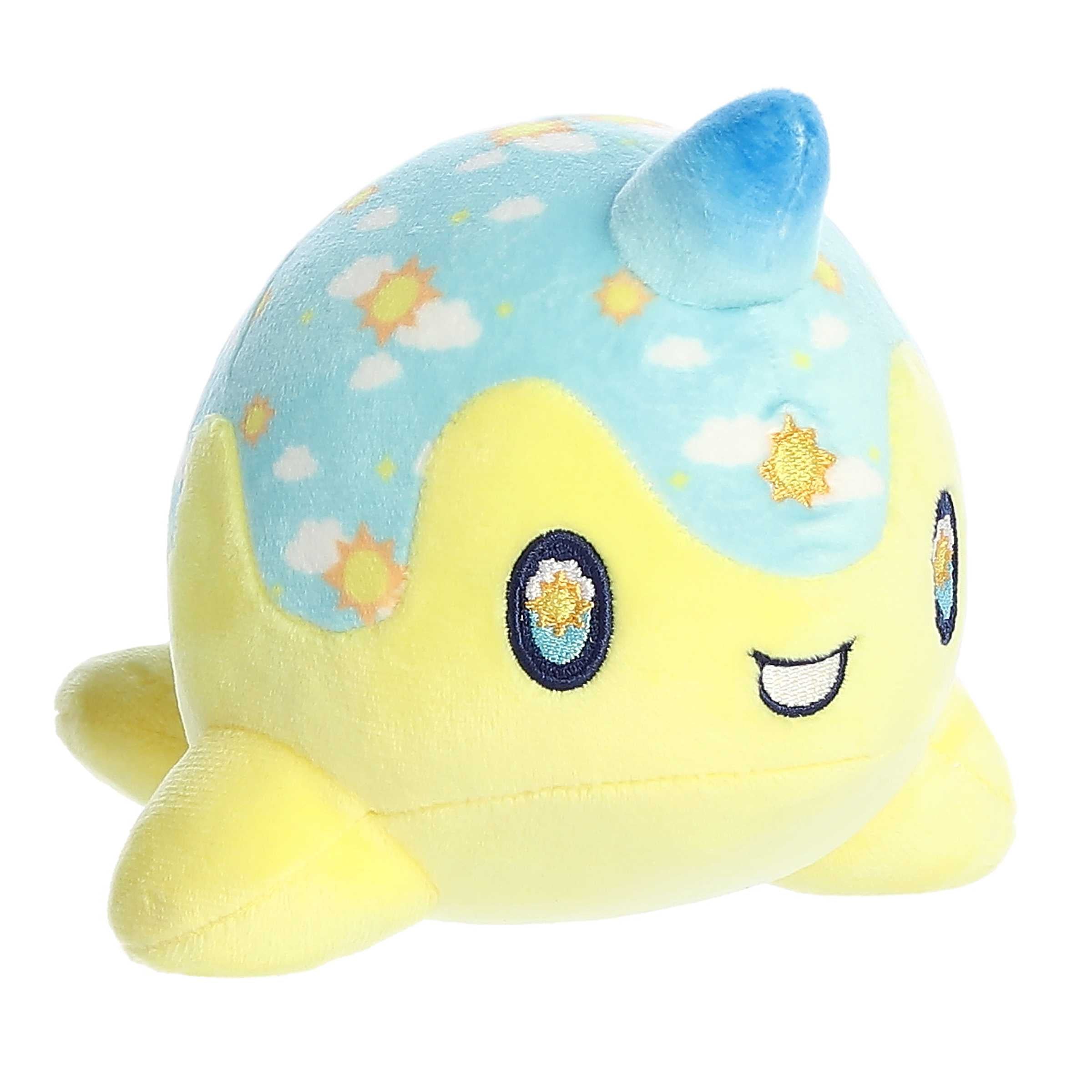 A yellow and blue Tasty Peach Nomwhal plush that is an expressive narwhal with big sparkling embroidered eyes