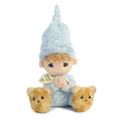 A plush doll from Precious Moments in a blue polka-dot nightgown with blonde yarn hair and bear slippers.
