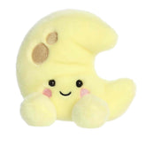 A small yellow crescent moon plush with embroidered craters and blushing cheeks from Palm Pals by Aurora.