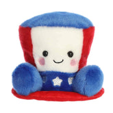 A small red, white, and blue hat plush with embroidered stars from Palm Pals by Aurora.