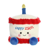 A large red, white, and blue cake plush with “Happy 250th” embroidery and a gold candle from Party-Sized Palm Pals by Aurora.
