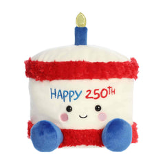 A large red, white, and blue cake plush with “Happy 250th” embroidery and a gold candle from Party-Sized Palm Pals
