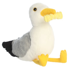A seagull plush toy from Aurora with white and gray fur, yellow accents, and a french fry in its beak.