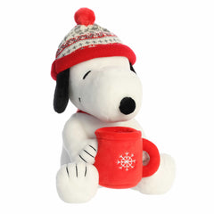 Snoopy plush wearing a festive winter hat and holding cocoa, crafted with soft materials