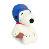 A Snoopy plush wearing a blue football helmet and holding a brown football from the Peanuts collection by Aurora.