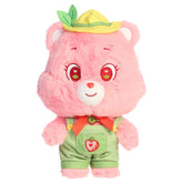 Cheer Bear dressed plush with pink fur, sweet smile, green outfit, and soft rounded ears