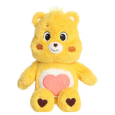 Tenderheart Bear plush with soft golden fur, sweet smile, round ears, and red heart belly badge