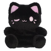 A black cat plush toy from Aurora with rounded paws, taro purple inner ears, and a matching winking expression.