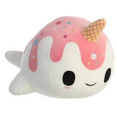 A pink and white Nomwhal plush toy from Tasty Peach Aurora with a waffle cone horn, sprinkles, and soft narwhal shape