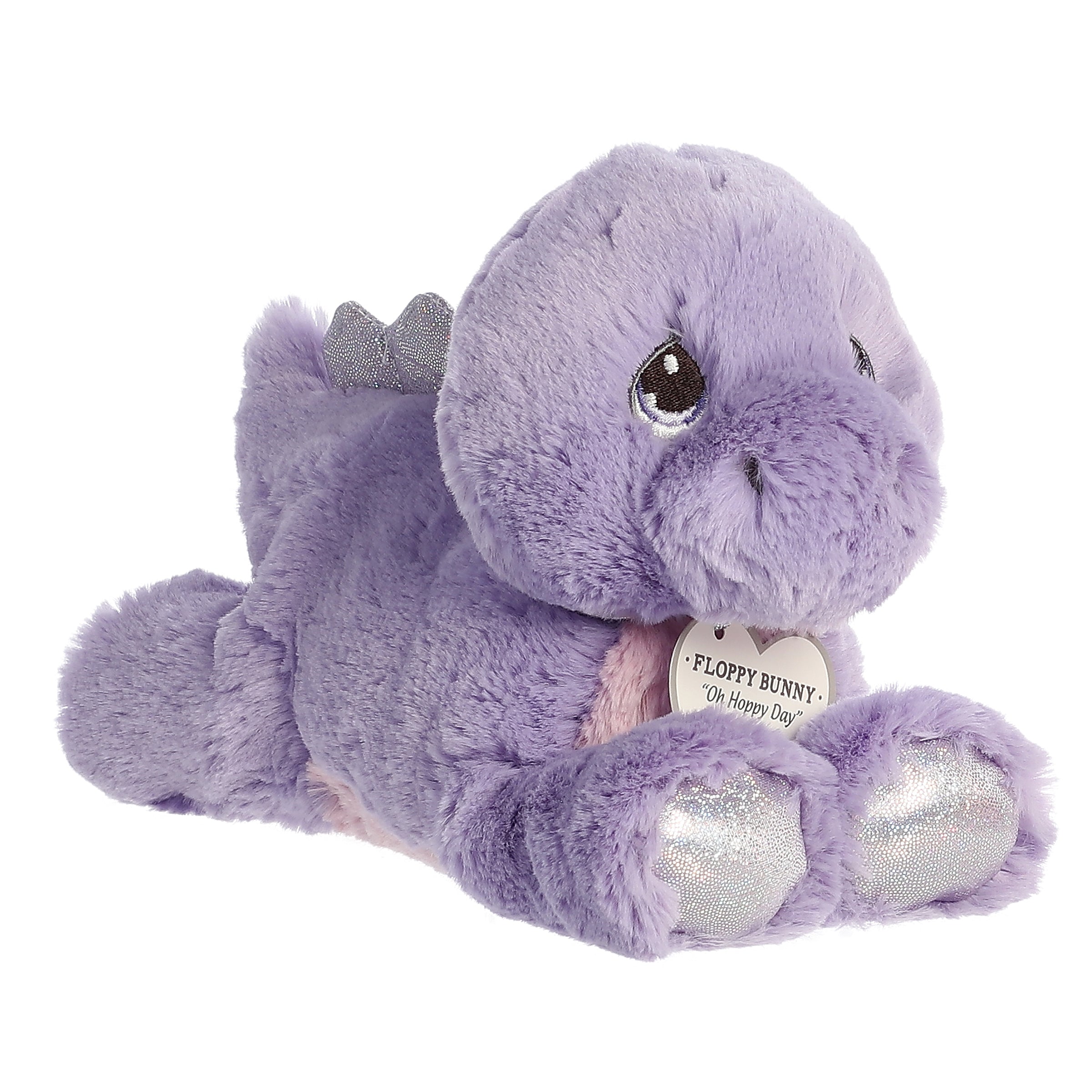 A laying down purple stegosaurus dino plush with tear-drop eyes and an inspirational tag around its neck.