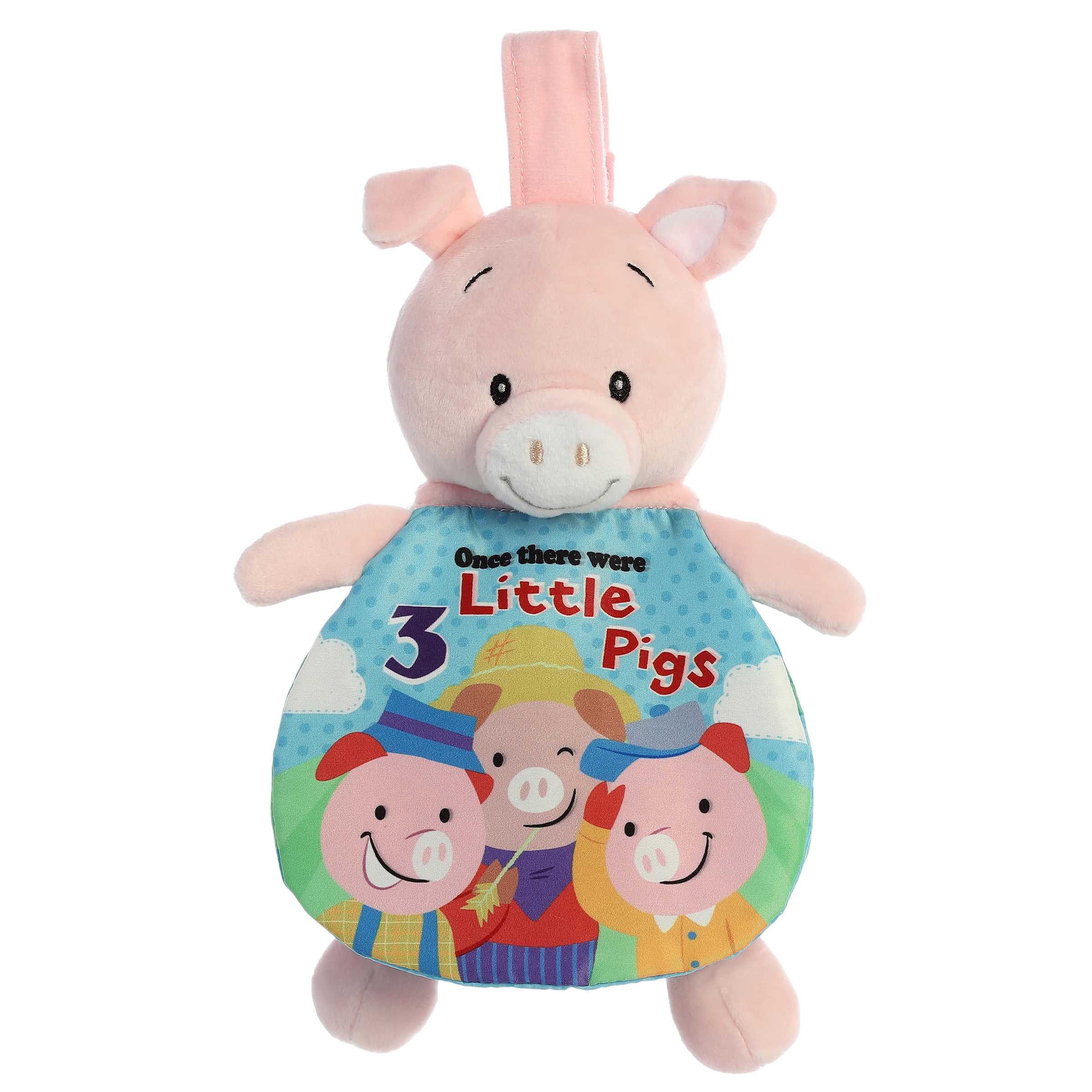 A pink pig plush toy from ebba by Aurora with an attached colorful crinkle book themed after the 3 Little Pigs story.