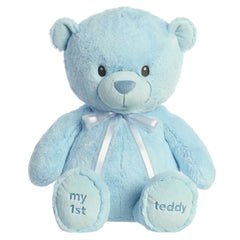 A blue teddy bear plush toy from ebba with embroidered eyes and a matching satin bow.