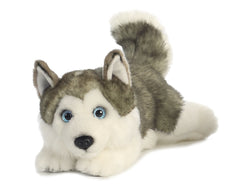 A Husky plush toy from Miyoni by Aurora, lying down with gray and white fur and bright blue eyes.