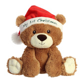 A brown bear stuffed animal wearing a red Santa hat embroidered with “My 1st Christmas.”