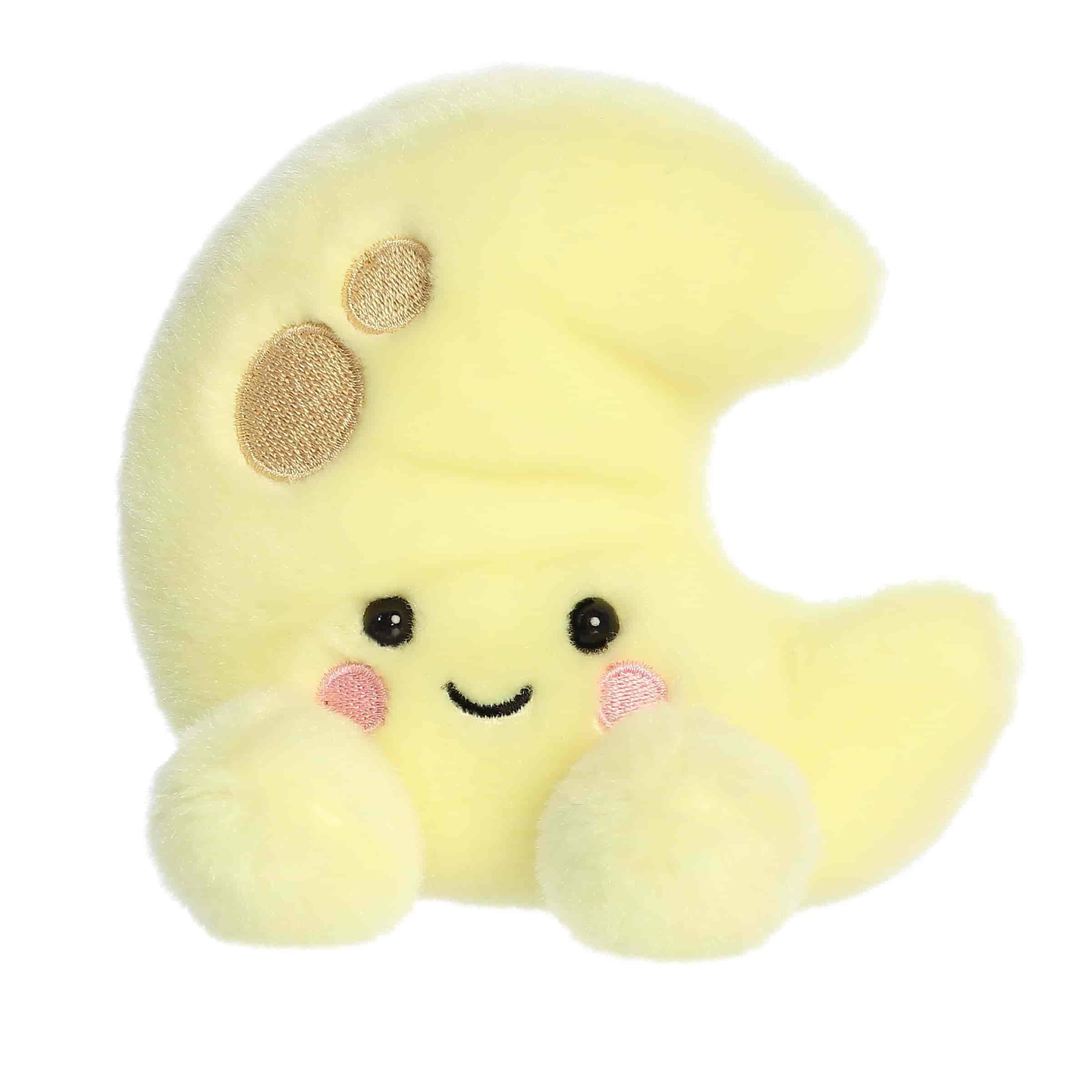 A small yellow crescent moon plush with embroidered craters and blushing cheeks from Palm Pals by Aurora.