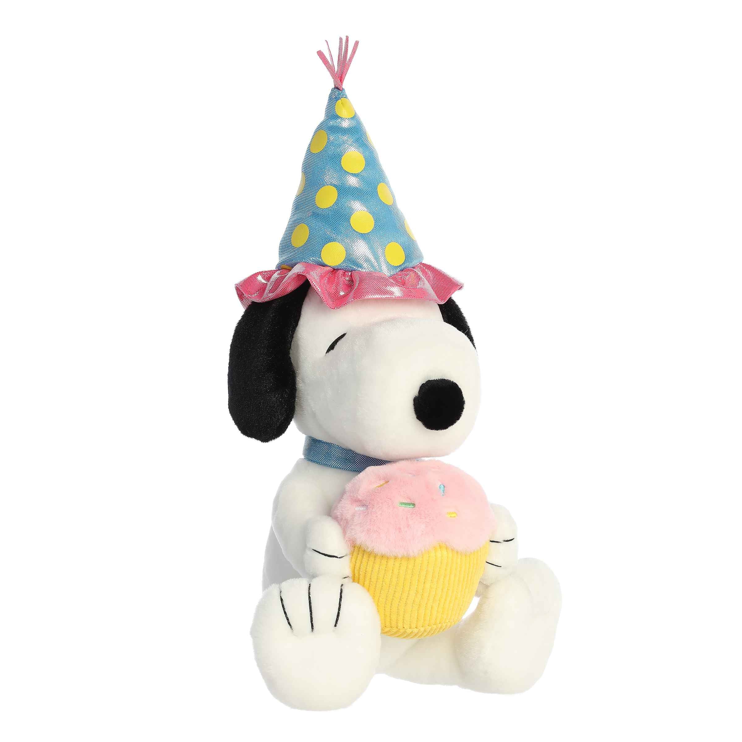 Plush of Snoopy wearing a party hat and holding a cupcake from the Peanuts collection