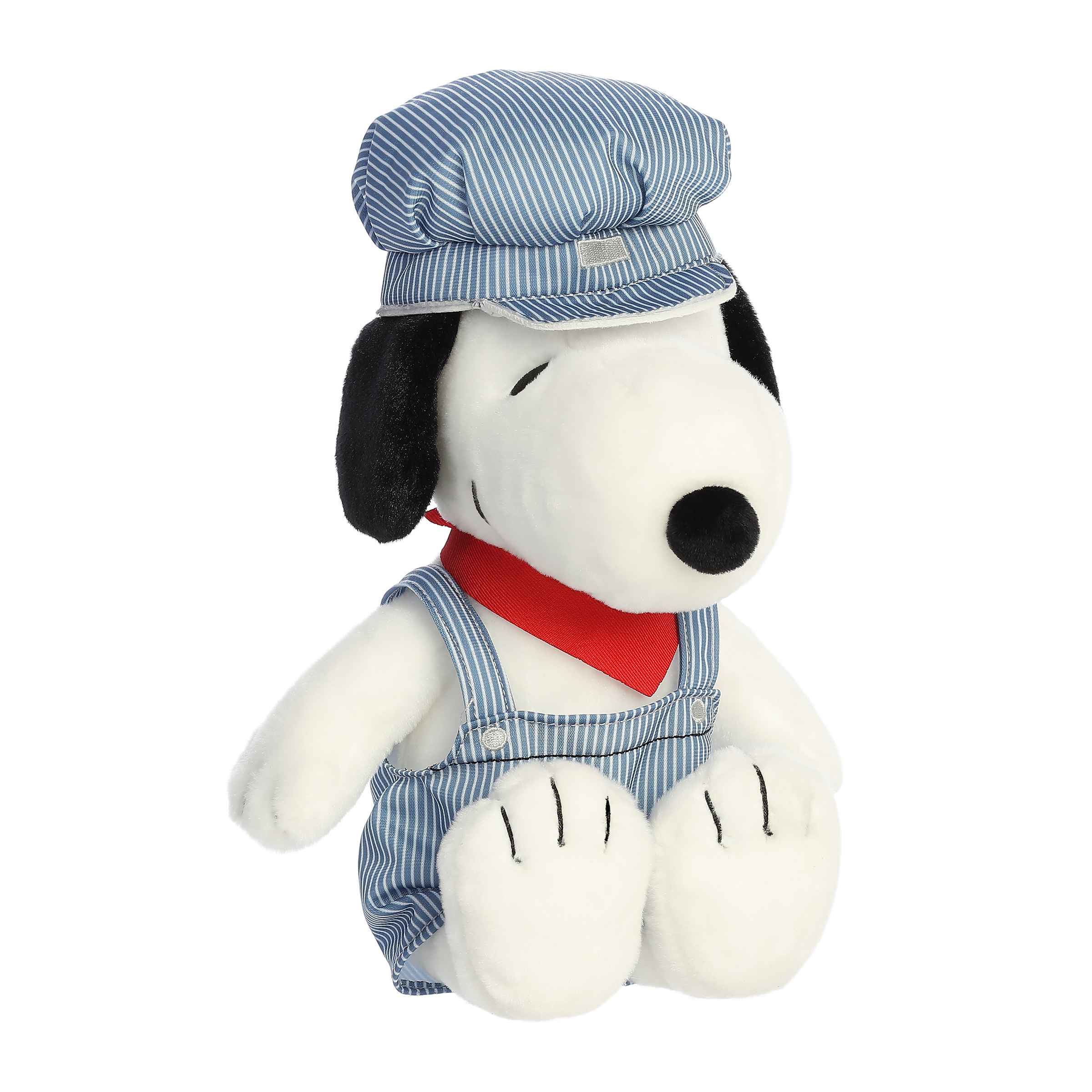 Plush of Snoopy dressed as a train engineer, wearing striped overalls, a matching cap, and a red neckerchief