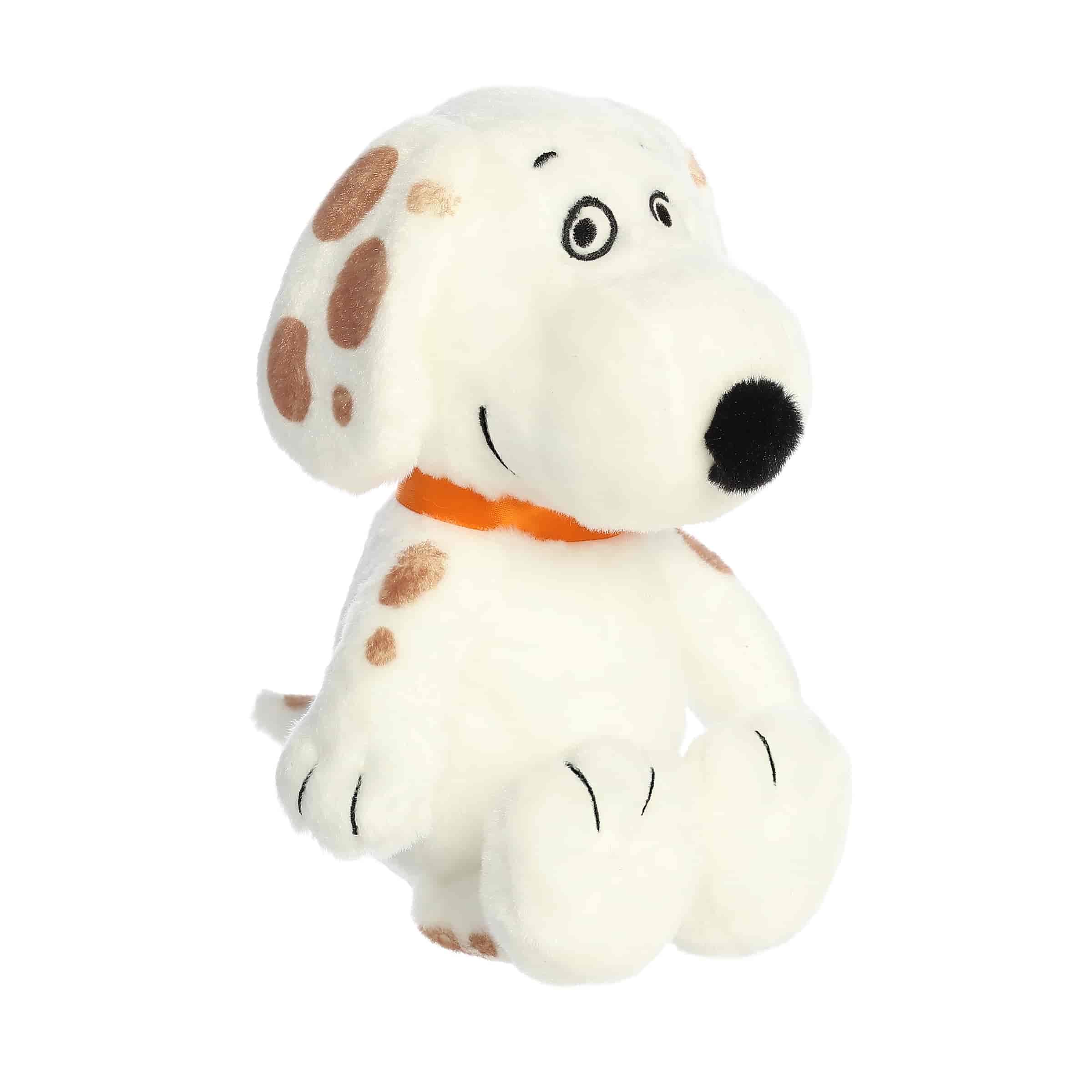 A Snoopy plush with white fur and brown spots lying down from the Peanuts collection by Aurora.