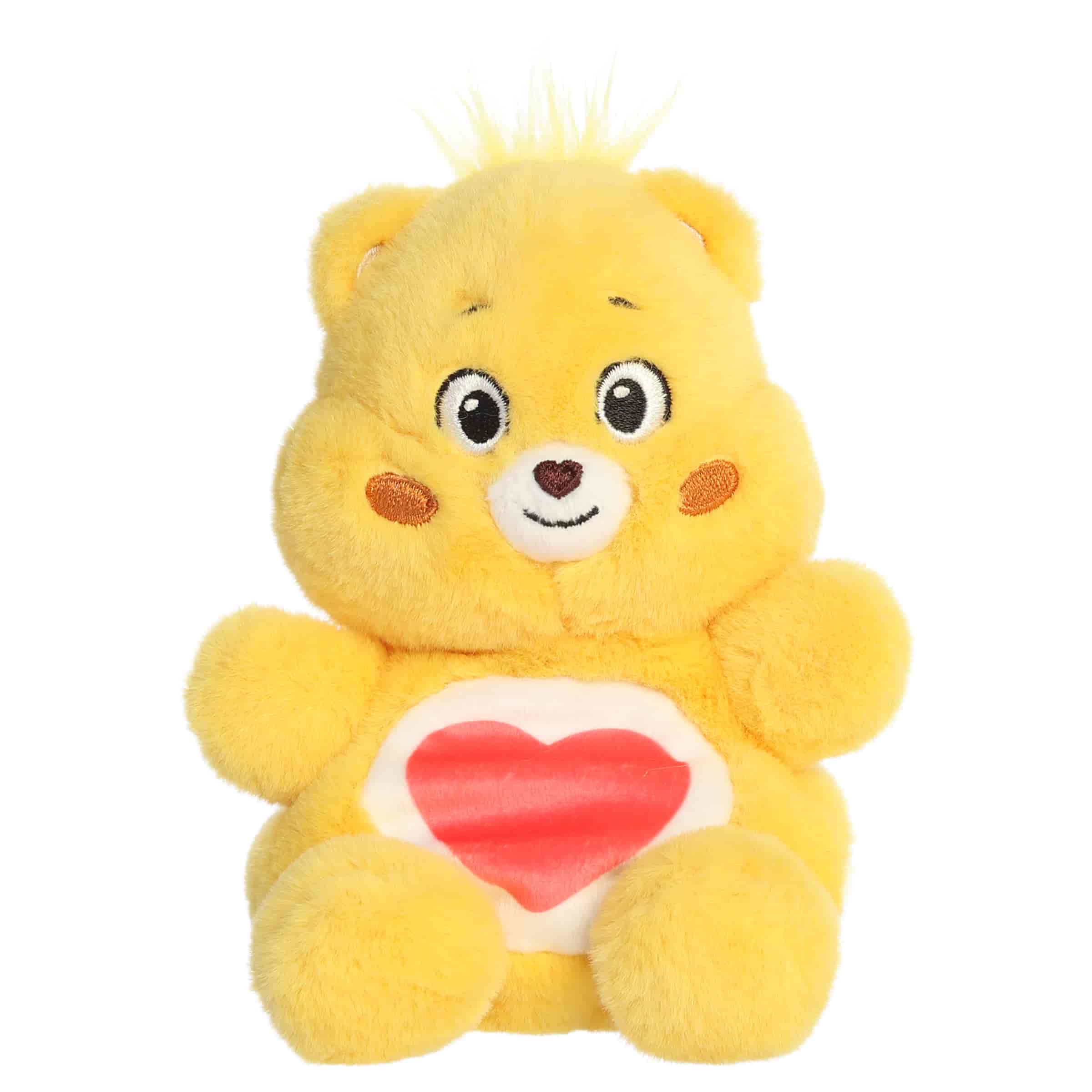 Tenderheart Bear Palm Pals plush with soft golden fur, gentle smile, round ears, and red heart belly badge