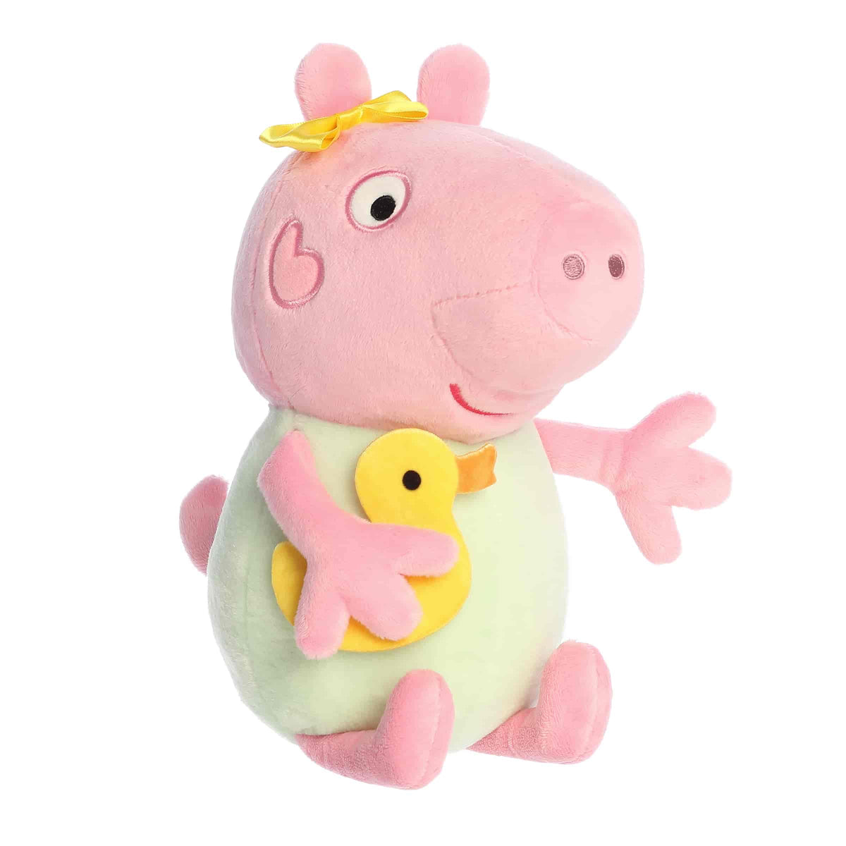 A Baby Evie plush wearing a green outfit and holding a yellow duck from Aurora’s Peppa Pig Collection.