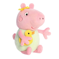A Baby Evie plush wearing a green outfit and holding a yellow duck from Aurora’s Peppa Pig Collection.