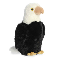 A plush eagle toy from Aurora with a white head, black body, and tan beak and talons.