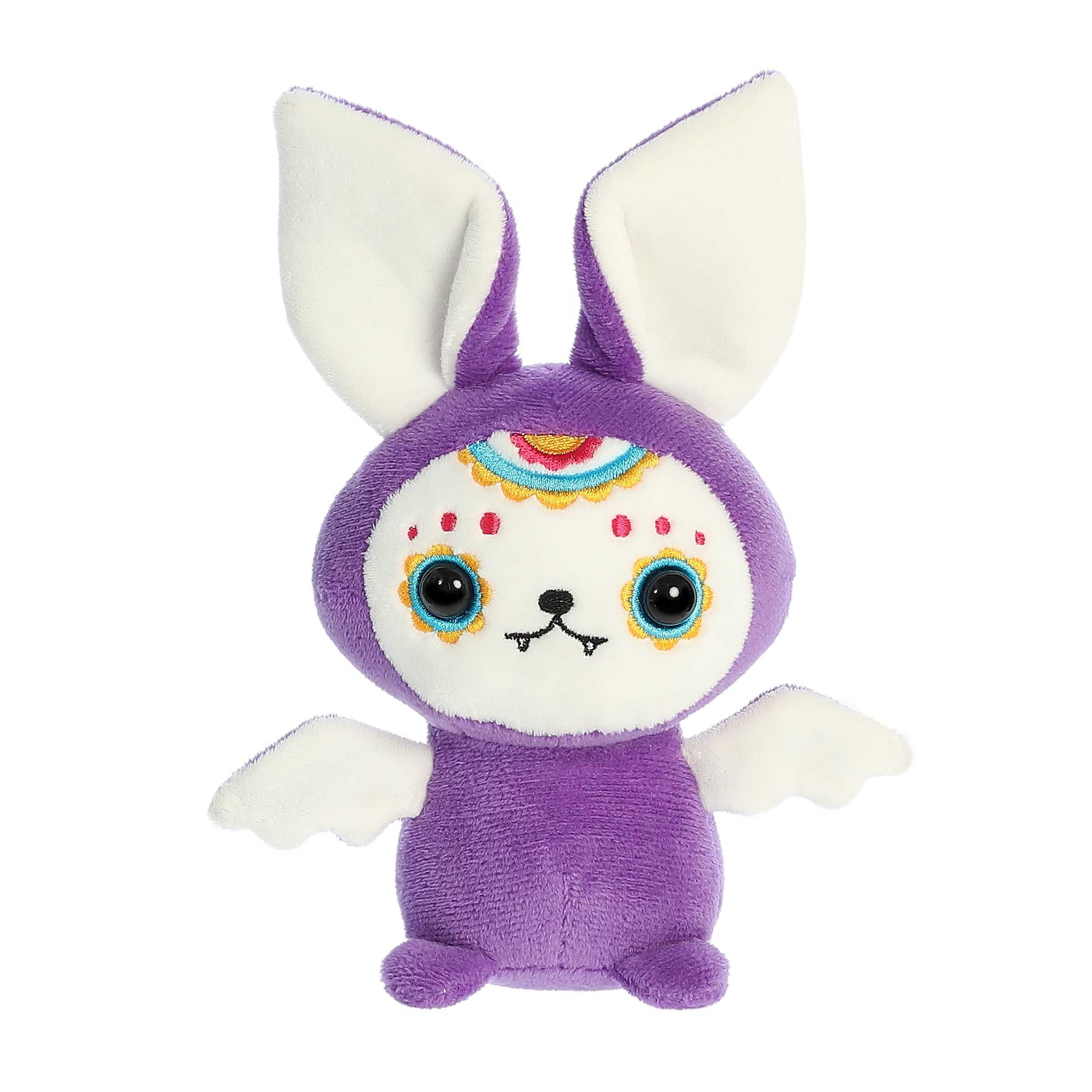 Purple bat stuffed animal with white ears and wings. Embroidered sugar skull painting details around the eyes and head.