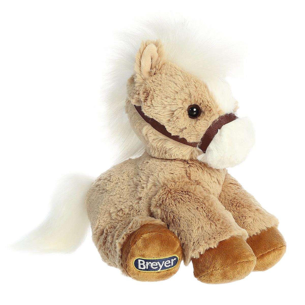 An adorably seated brown and white Breyer Palomino horse plush with a tan coat, a white snout, and brown reigns.