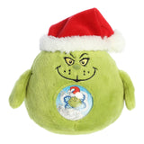 Round green Grinch character plushie with red Santa hat and magical globe belly of snowflake confetti
