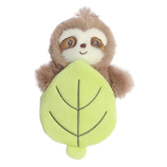 Adorable brown sloth plush rattle toy with dark brown accents on eyes sitting inside a crinkly green leaf pocket