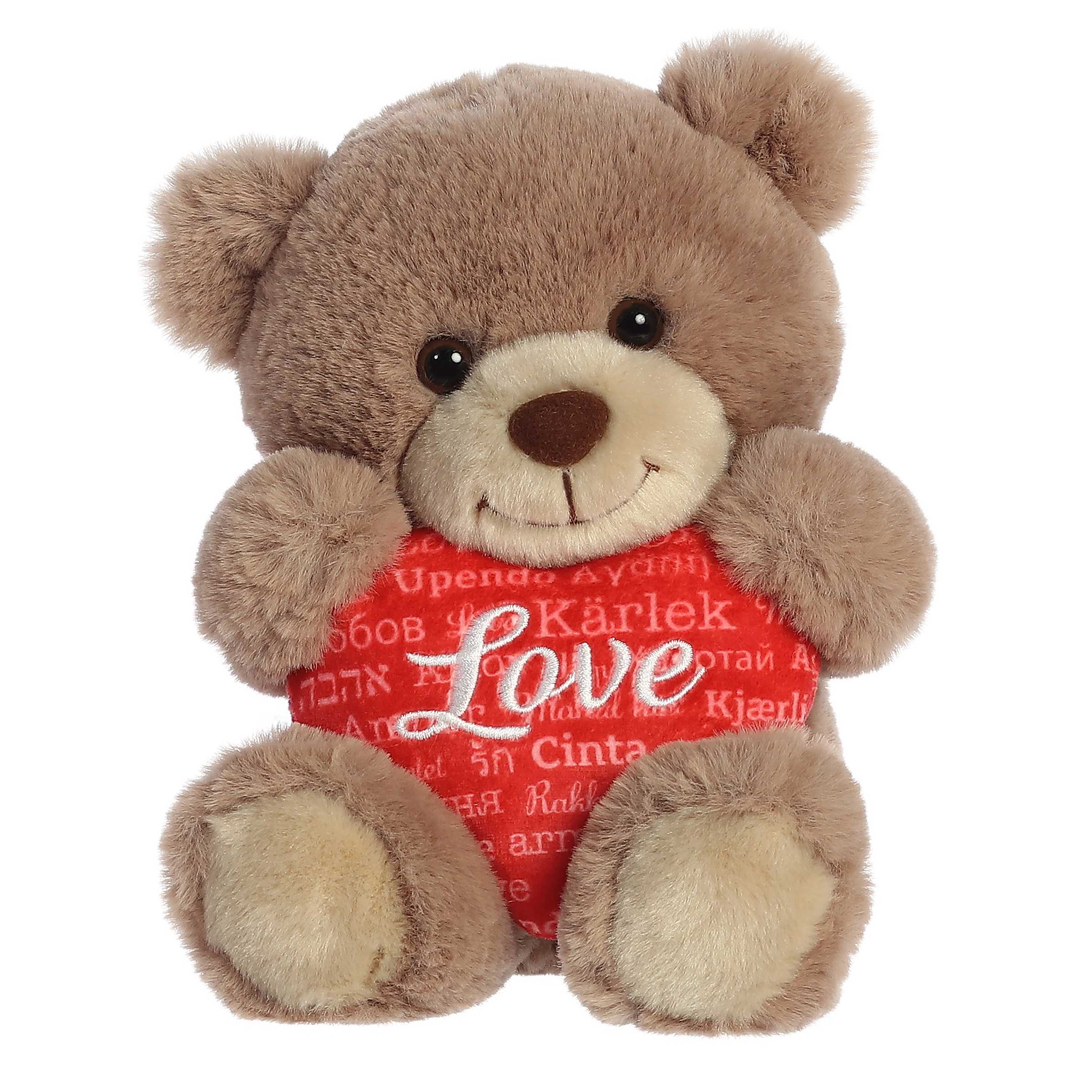 Soft taupe bear plush, holding a red heart with 'Love' in different languages. Symbolizing global affection and unity.