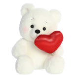 Soft, cream-furred Bashful Bear plush, holding a red heart and blushing, embodying charm and affection for Valentine’s Day