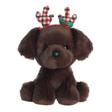 Adorable chocolate lab puppy in a sitting position wearing plaid colored holiday antlers
