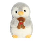 Adorable light grey penguin with a yellow beak and feet holding a smiling gingerbread man cookie with a red bow